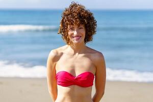 alegre mujer en bikini en playa durante soleado día foto