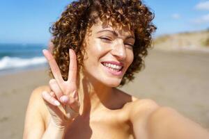 Happy woman showing V sign on beach photo