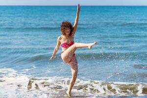 despreocupado mujer salpicaduras Oceano agua en playa foto