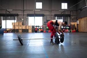 Woman preparing weights to dead-lifting in an empty gym photo