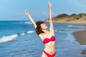 Happy woman in swimwear enjoying freedom at beach photo