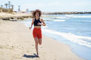 Fit sportswoman running on sandy beach photo