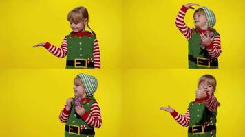 Kid girl in Christmas elf Santa helper costume points fingers at blank space shows advertising area video