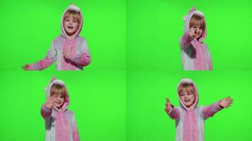 Little child girl smiling, waving greeting, hello or bye with hand in unicorn pajamas on chroma key video