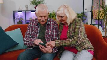 étonné Sénior grands-parents utilisation mobile téléphone intelligent recevoir bien nouvelles message sous le choc par soudain la victoire video