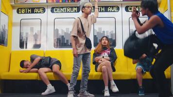 Passengers in a colorful subway car, with a young person standing and holding a handrail, others seated and looking at phones. video