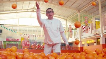 Confident chef standing in a market with oranges in the foreground and festive decorations. video