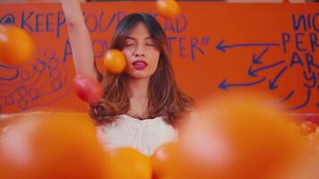 Confident young woman posing with hand raised against a vibrant orange graffiti wall, exuding a rebellious and edgy vibe. video