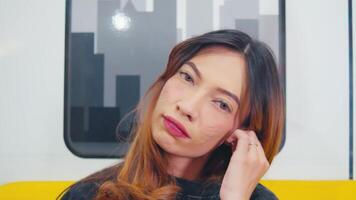 Portrait of a young woman with closed eyes, seemingly daydreaming or relaxing, inside a train with a blurred background. video