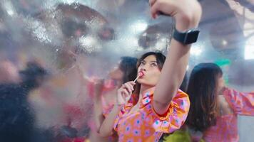 Young woman taking a selfie at a vibrant party with disco ball and festive lights. video