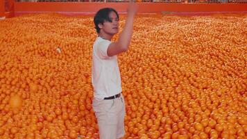 hombre caminando mediante un almacén lleno con naranjas, industrial agricultura concepto. video