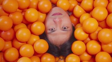 Woman surrounded by oranges, creating a vibrant and playful background. video