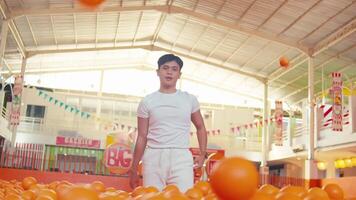 Confident man standing in a colorful ball pit with hands on hips, indoor playground setting. video