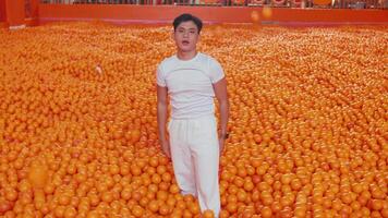 Man talking on phone while standing in a sea of oranges. video