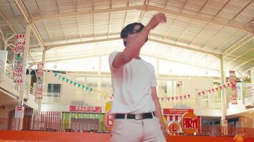 sonriente joven hombre en un blanco camiseta y Gafas de sol en pie en un festivo interior ajuste con vistoso decoraciones video