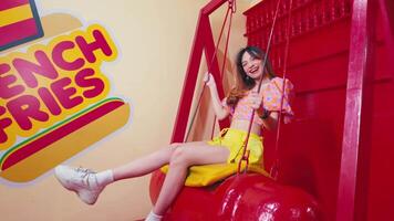 a girl playing on a red swing while smiling happily in a colored room video