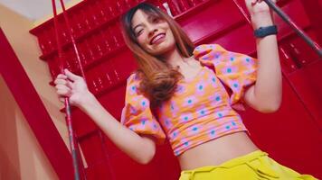 a girl playing on a red swing while smiling happily in a colored room video