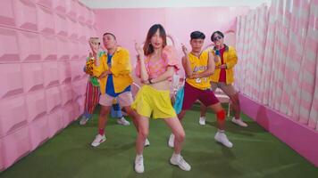 grupo do na moda jovem pessoas dançando dentro uma colorida, estilizado quarto com uma Rosa pano de fundo. video