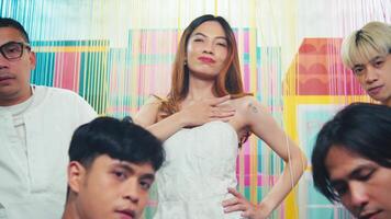 Group of young adults in white outfits posing with attitude in front of a colorful striped background. video