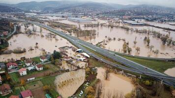 Aerial drone view of torrential rain causes flash floods in residential areas. Houses and roads surrounded by water. Climate change. Heavy rainfall consequences. photo