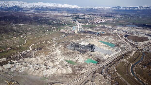 Aerial view of working mine pit. Drone shot of coal mining activity. Artificial polluted lakes. Mountains with snow in the background. Extraction. Machine working. Destroyed landscape. photo