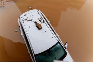 torrencial lluvia causas destello inundaciones en el ciudad área. carros debajo agua en el condominio estacionamiento lote. dañado carros causado por pesado lluvia. edificios rodeado por agua. foto