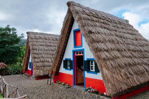 Santana Typical Houses in Madeira Island. These small, triangular and colorful houses represent a part of the Madeira heritage and one of the most popular tourist attractions of the island. photo