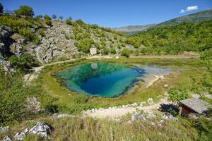 The Eye of the Earth, Croatia Cetina River Source. Church in the background. Rural tourism and travel destinations. photo