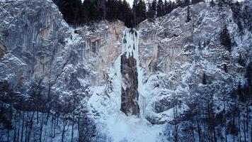 Aerial drone view of a partially frozen waterfall. Beautiful and magical winter holiday scenery for nature lovers. Skakavac waterfall in Sarajevo, Bosnia and Herzegovina. photo