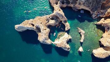 Aerial drone shot of kayaks and boats passing around magical Ponta da Piedade limestone cliffs. Exploring caves and tunnels of Lagos, Algarve, South of Portugal. Travel and adventure. Nomad life. photo