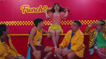 Stylish young people posing in front of a vibrant French and Fries backdrop, exuding urban fashion and confidence. video