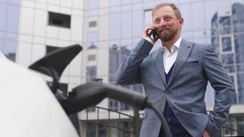 homme d'affaire bouchage électrique voiture de mise en charge gare. Sénior est bouchage dans Puissance corde à un électrique auto. mise en charge électrique voiture à mise en charge station video