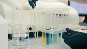 Laboratory Technician testing Soil in Lab Room. Researcher in black Rubber Gloves inserting Tube from Automated Machine into Containers with blue and yellow Liquids video