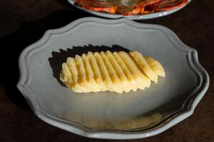 A traditional Alentejo cheese, neatly sliced on a ceramic plate. The golden-brown rind contrasts with the creamy white interior, creating an inviting and visually appealing presentation. photo