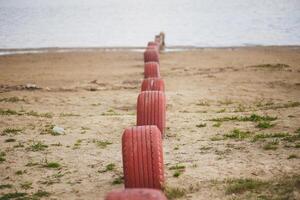 un fila de rojo llantas en el arenoso playa de el báltico mar. foto