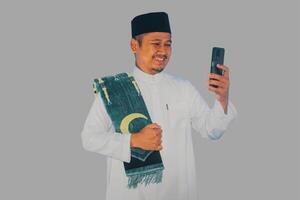 Moslem Asian man clenched fist showing excitement when looking to his mobile phone photo