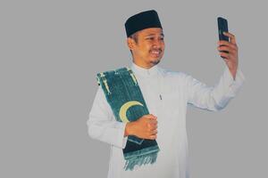 Moslem Asian man clenched fist showing excitement when looking to his mobile phone photo