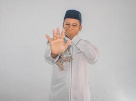 Moslem Asian man cover his mouth with hand while smiling. Bad breath concept during fasting month photo