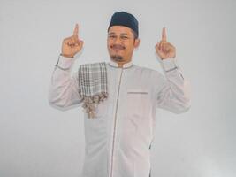 Moslem Asian man smiling at the camera with both hands pointing up photo