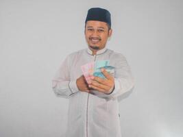 Asian moslem man holding money with grateful gesture photo