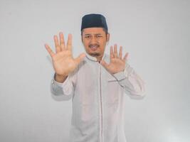 Moslem Asian man give stop hand sign with serious expression photo