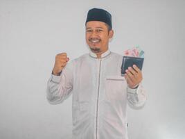 Muslim Asian man clenched fist showing happiness when holding a wallet full money photo