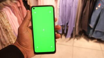 Mens Holding slim telefoon met groen scherm binnen van een vrouw kleding op te slaan video