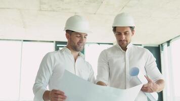 Two men in helmet look at the plan of the building video