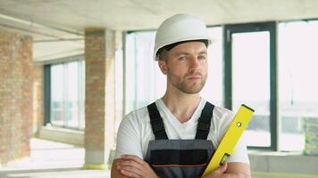 portrait de un ingénieur dans une casque avec Jaune équilibre règle à une construction placer. bulle niveau règle proche en haut voir, mesure et nivellement concept video