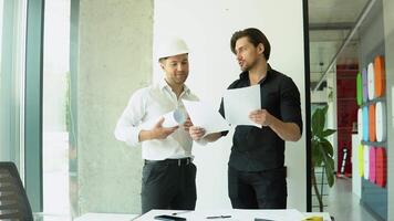 Two architect discussing help create plan with blueprint home building at office video