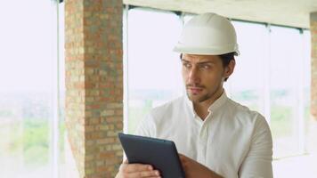 Engineer builder architect with safety helmet with tablet, looking on new building on site video