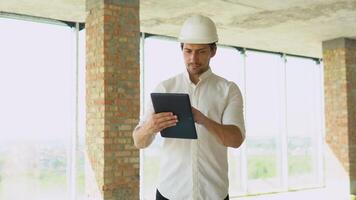 ingénieur développeur dans casque avec tablette inspecter bâtiment. constructeur constructeur spécialiste. civil ingénieur architecte construction site video