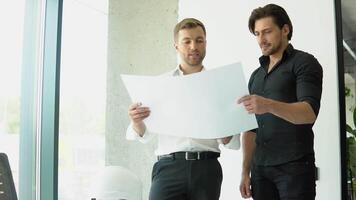 Two architect discussing help create plan with blueprint home building at office video