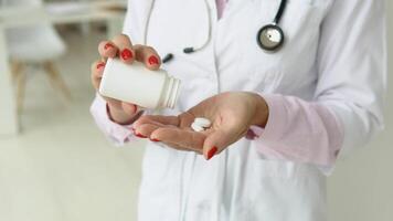 Female doctor in white coat takes pills out of a jar. Close up view of hands video